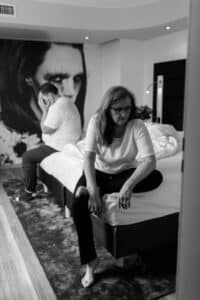 Nähe wieder herstellen. Wenn sprachlosigkeit Raum einnimmt wird das zur Belastung einer Beziehung. Ein Paar sitzt auf dem Bett, beide wirken sehr traurig und hilflos.